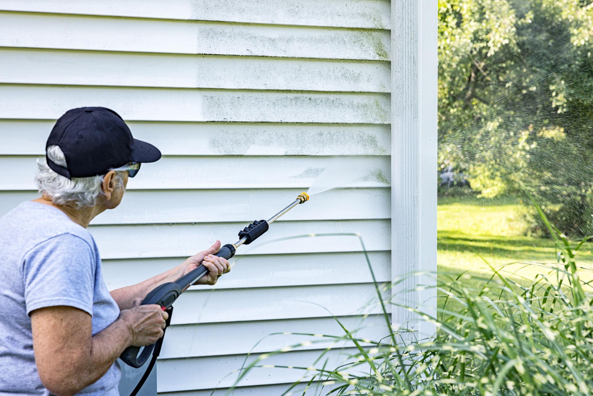 Woman Homeowner DIY Power Washing House Siding and Downspout
